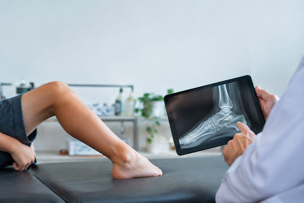 Un médecin montre une radiographie du pied d'un enfant sur une tablette numérique lors d'une consultation médicale.